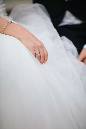 Close up brides hand with silver eye gem ring rest on knee on wedding ceremony. Details and wedding accessoriesの写真素材