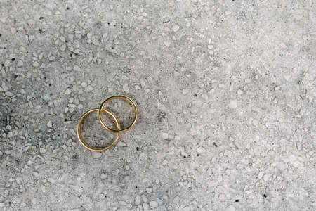 Top view two golden wedding rings lay on white tiny stones copy space backgroundの写真素材