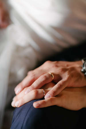 Close up detail of female and male hands of newlyweds at weddings displaying gold wedding ringsの写真素材