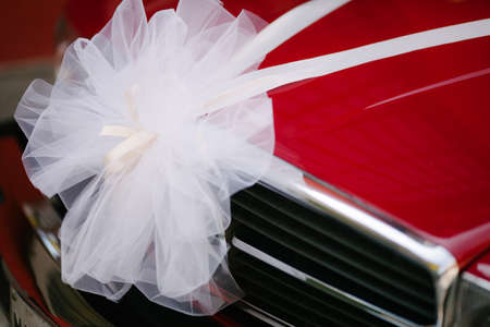 White big ribbon in front of red car grille displayed with blank copy space backgroundの写真素材