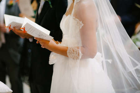 Close up wedding couple hands hold personalized vows notes in wedding ceremony in churchの写真素材