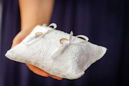 Female hand show wedding rings decorated on white cushion set upの写真素材