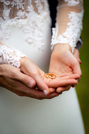 Female and male hands together hold and show in palm wedding ringsの写真素材