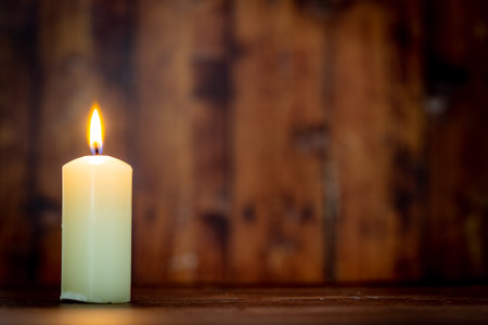 Burning candle on a wooden background, shallow depth of field.の写真素材