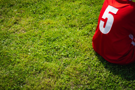 Red football jersey on the grass in the stadium. Selective focus.