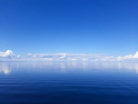 The blue water connects with the blue sea. Blue photo background. Calm on the lake and sunny weatherの写真素材
