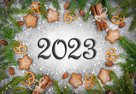 Feat lay Christmas background with cookies, fir branches and sweets. New Year 2023 lettering...