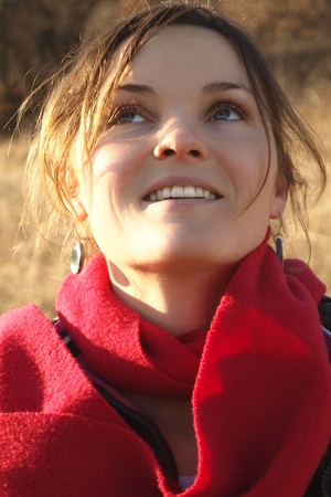 Happy young woman with a red scarf looking at the sky and smilingの写真素材