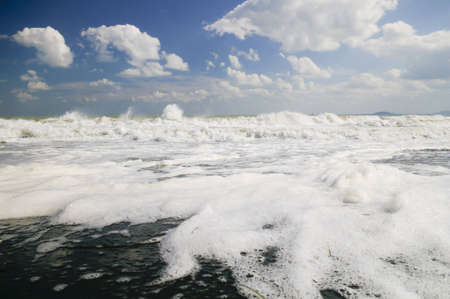 Strong wind creates big waves crashing onto the black sandy beachの写真素材