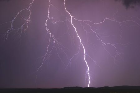 Lighting strikes through the night sky during a summer stormの写真素材
