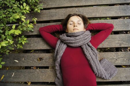 Beautiful young woman dreaming on a wooden bridge の写真素材
