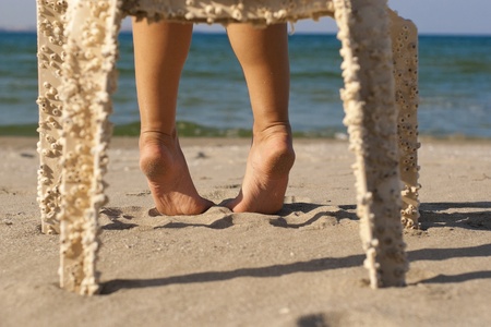 Lovely female feet stepping on the hot sand on the beachの写真素材