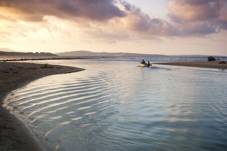 Small boat sails out of Idyllic Estuary at duskの写真素材