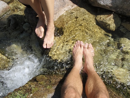 Bare male and female legs relax in a river