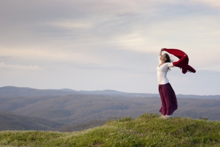 Beautiful young woman standing on top of mountain feeling empowered expressing joy and freedomの写真素材