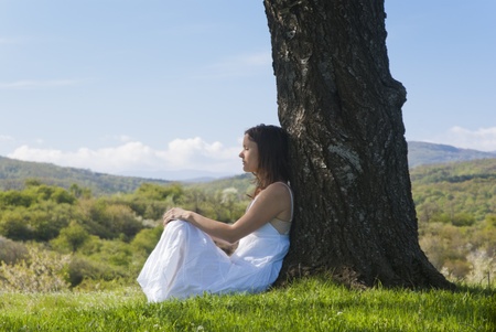 Beautiful young woman meditating under a cherry tree in bloomの写真素材