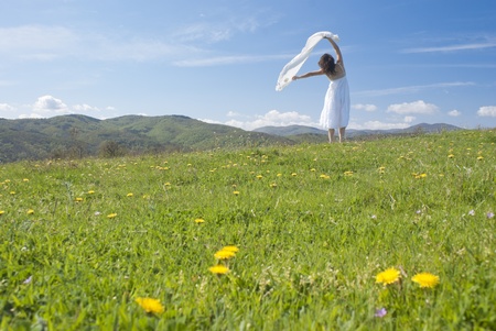 Beautiful young woman with a white dress enjoying the freedom of being outdoors in springtimeの写真素材