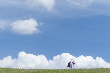 Beautiful young girl with white dress enjoying the sunny day on a green meadow under the blue skyの写真素材