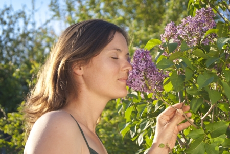 Girl smelling a scented lilac on a sunny dayの写真素材
