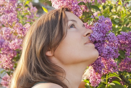 Beautiful young woman enjoying the scent of a lilac flowerの写真素材