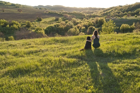 Beutiful young woman and her dog watch sunset togetherの写真素材