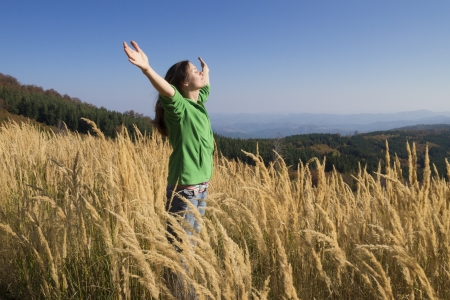 Happy young girl enjoying the beauty of sunny autumn day high in the mountainsの写真素材