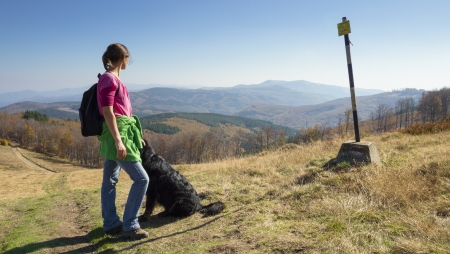 Slim young girl walking in the mountains with her dog looking at a singpostの写真素材