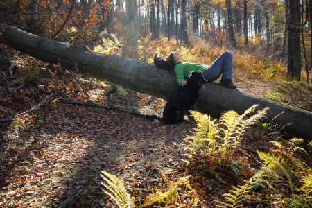 Beautiful young girl wearing green top  lying on a fallen tree trunk and relaxing deep into the forestの写真素材
