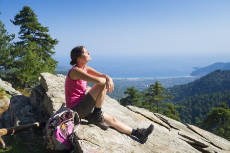 Beautiful fit young woman hiking up a mountain and enjoying the panoramic view on the island of Thassos, Greece.の写真素材