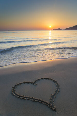Heart shape drawn on a  sandy beach at sunrise on the beautiful island of Thassos, Greece.の写真素材