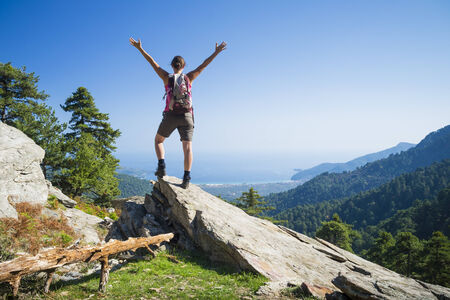 Beautiful fit young woman hiking up a mountain and enjoying the panoramic view on the island of Thassos, Greece.の写真素材
