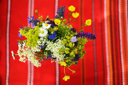 Wild flower bunch shot from above with a red decorated table cloth in the background.の写真素材