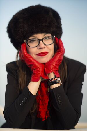 Young woman with a beautiful smile wearing red lipstick and big fur hat on a sunny winter day.の写真素材