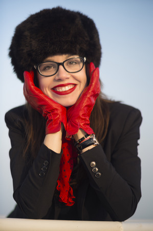 Young woman with a beautiful smile wearing red lipstick and big fur hat on a sunny winter day.の写真素材