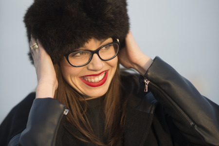 Beautiful young woman with big fur hat having fun on a sunny winter day.の写真素材