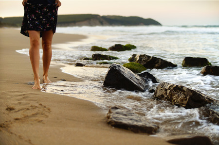 Female legs walking on the beach on a warm summer evening.の写真素材