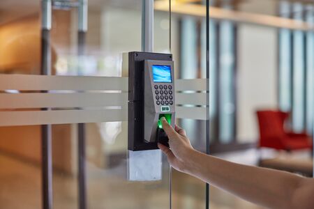 Yong man or woman push fingers down the electronic control machine to access the digital door locking system. Selective focus at hand.の写真素材