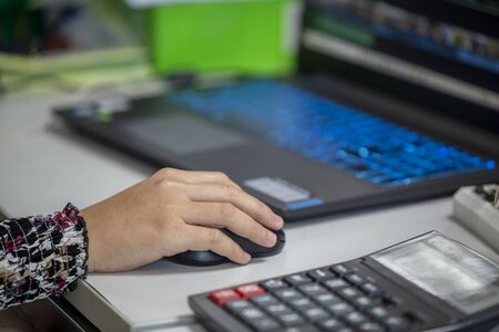 young man or woman by using computer mouse for working. finance or business concept. Close up and selective focus.の写真素材