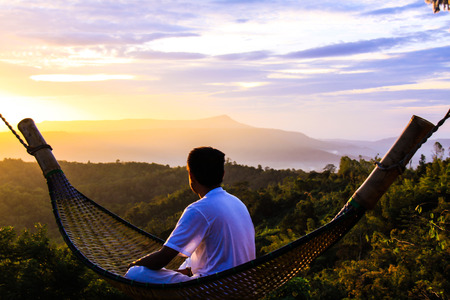 Portrait of a man sitting on a wooden cribs watching the sunrise