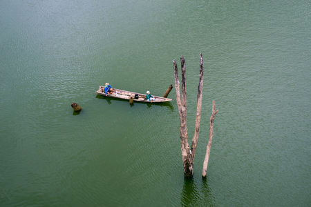 A fisherman rides long tail boat across Songkhalia river, Sangkhlaburi, Kanchanaburi, Thailand.の写真素材