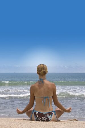 attractive young woman in yoga pose at the beachの写真素材