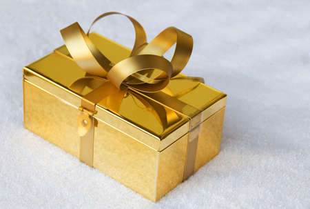 gold giftbox with bow on white の写真素材