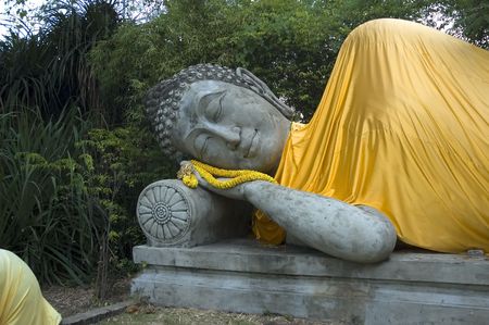 Buddah in a reclining position with winter robe and flowersの写真素材