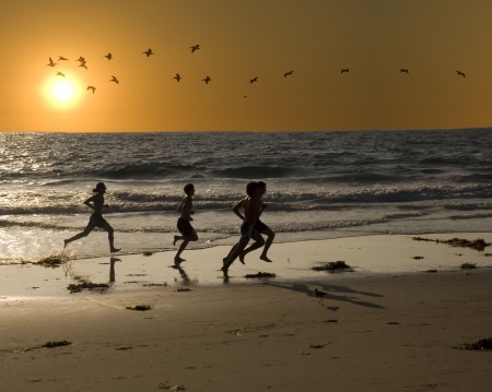 a group of young men are exercising by jogging on the beach for fitnessの写真素材