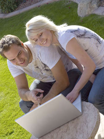 Attractive young couple outdoors with computerの写真素材