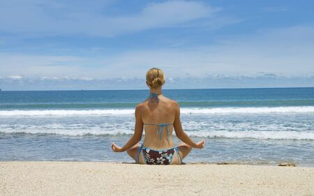 attractive young woman doing yoga at the beach の写真素材
