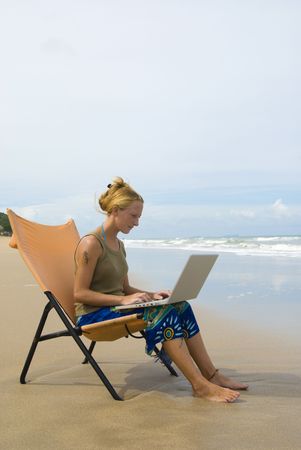attractive young woman with notebook computer at the beachの写真素材