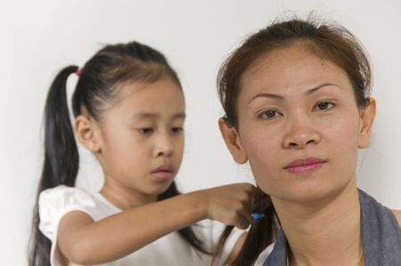 Asian Mom is having her hair braided by her daughterの写真素材