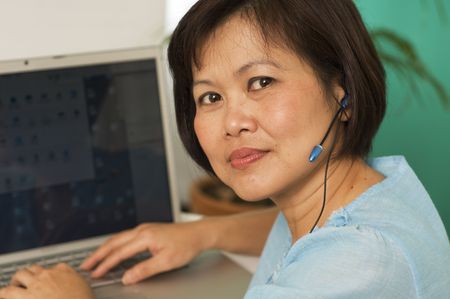 Attractive Asian business woman wearing headset and smilingの写真素材