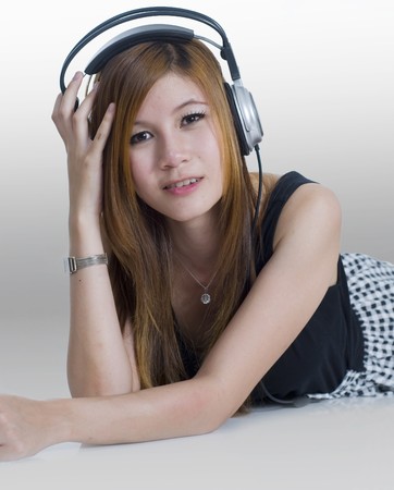 Sexy young girl laying down listening to music on headphonesの写真素材